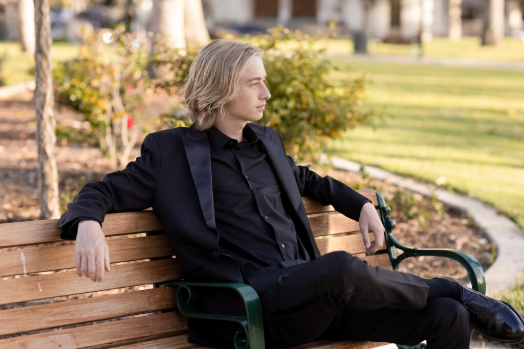 High School Senior sitting on a bench looking a way with many thoughts at his portrait session.